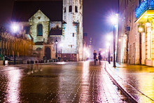 Night Street In The Krakow, Poland. Colorful Night Illumination Reflecting In The Wet Stone Pavement Of The Old Town. Beautiful Background Photo.