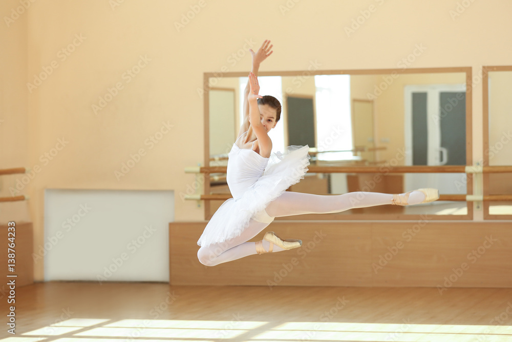 Young beautiful ballerina dancing in dance hall