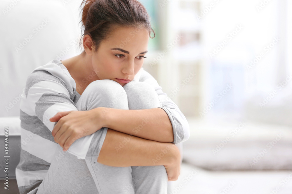 Depressed young woman sitting on floor at home - obrazy, fototapety, plakaty 