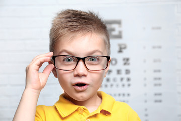 Little boy with spectacles on ophthalmic test chart background