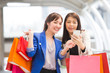 © Bavorndej - Happy shopping asia woman use smartphone with friends at the background.