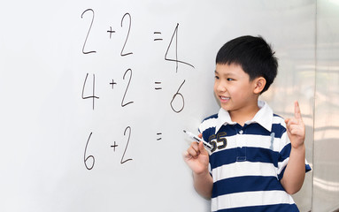 Young Asian boy has a math exercise on white board with a blank answer and he is thinking about it.