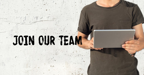 Wall Mural - Young man using tablet pc and JOIN OUR TEAM concept on wall background