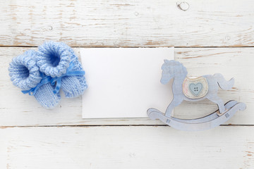 Greeting children form with blue booties and wooden horse. Flat lay