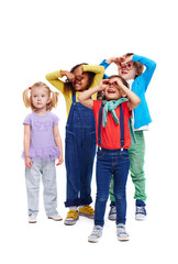 Studio portrait of children against white background: full body shot of group of kids dressed in colorful clothes standing close together making faces and looking up