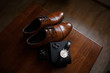 Wedding accessories for groom: brown shoes, cufflinks, hand watch and wedding rings on wooden table