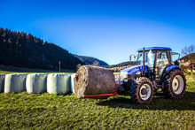 Tractor Carrying Hay Bale Rolls - Stacking Them On Pile.