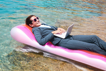 Wall Mural - Happy businesswoman using laptop on pool raft