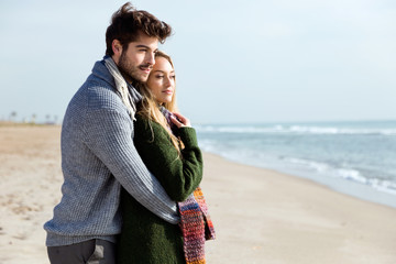 Beautiful young couple in love in a cold winter on the beach.