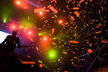 Wall Mural - Silhouette of guitarist musician on stage at a concert and flying confetti