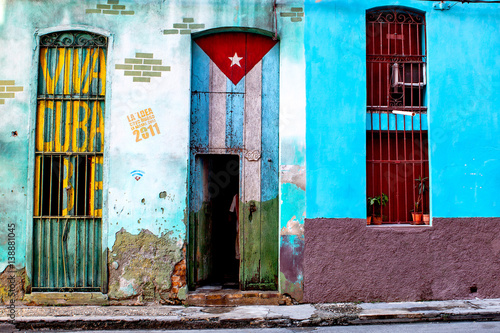 Obraz Dibond Stary odrapany dom w środkowej Hawanie malowany kubańską flagą i napisem Libra „Viva Cuba”