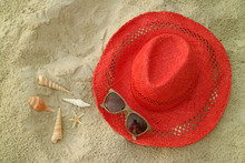 Red Straw Hat And Brown Sunglasses On The Sand Beach With Many Types Of Seashells
