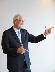 Funny senior businessman showing shooting gesture