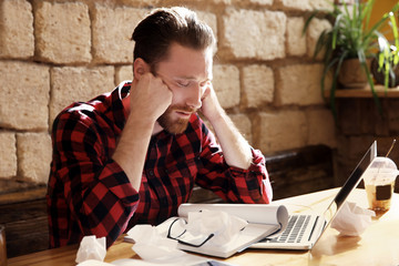 Handsome young man tired of working on computer at cafe