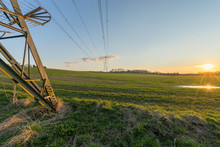 Meadow And Electricity Pylon - UK Standard Overhead Power Line Transmission Tower At Sunset