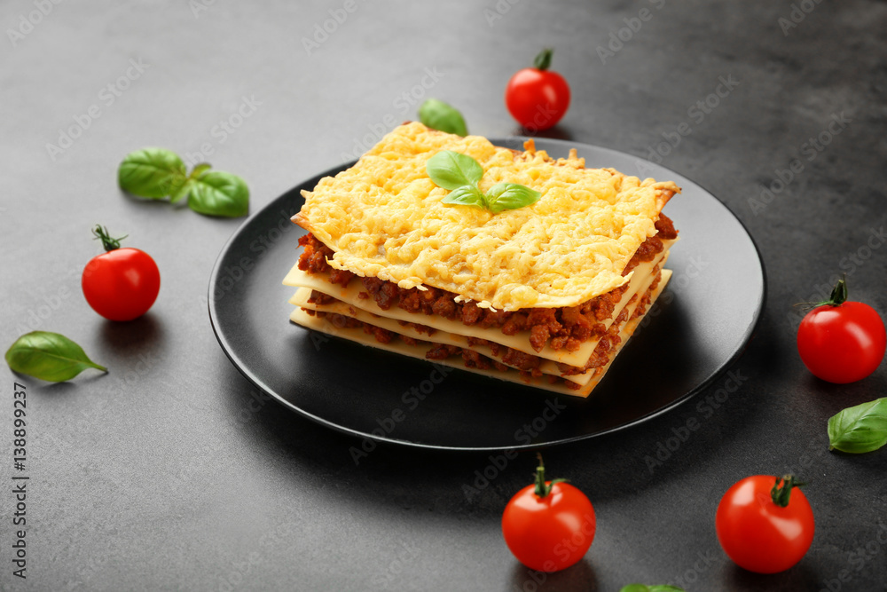 Plate with tasty lasagna on gray background