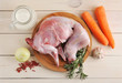 raw rabbit on a wooden Board with ingredients for stewing milk, onion, carrot, rosemary