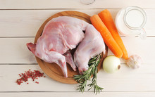 Raw Rabbit On A Wooden Board With Ingredients For Stewing Milk, Onion, Carrot, Rosemary