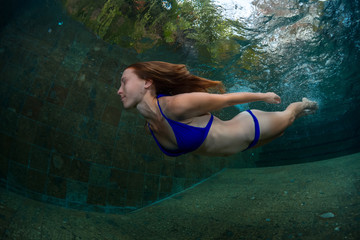 Young lady swimming underwater in the pool