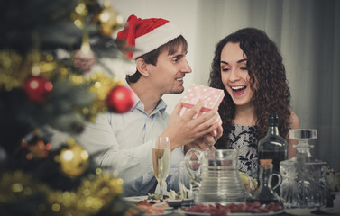 Man giving present to happy  woman during Christmas dinner