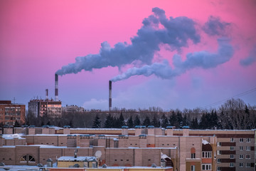 Purple winter sky and smoking plant pipes over the industrial city