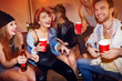 © pressmaster - Group of drunk young people chilling at house party, laughing and drinking beer sitting on couch