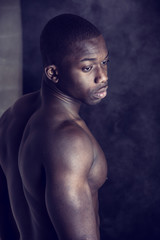 Wall Mural - African American bodybuilder young man, naked muscular torso, on dark background