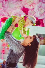 brunette woma with long hair raises up little girl in green clothes