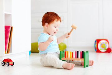 Wall Mural - cute infant baby playing with wooden hammer block toy