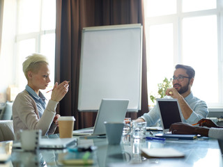 Canvas Print - Portrait of two creative business people having long discussion over work related issues thinking and sharing ideas while sitting at messy meeting table