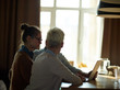 © pressmaster - Side view portrait of several creative business people sitting together at table in dim room, having discussion meeting and looking at laptop screen
