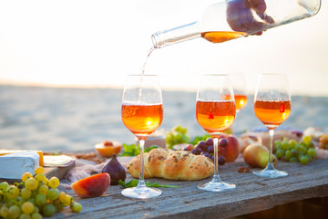 Picnic on the beach at sunset in boho style, food and drink concept