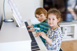 © Irina Schmidt - Two little kids girl and boy playing piano in living room or music school