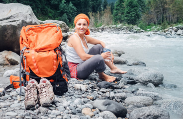 Backpacker female relax on the mountain river bank