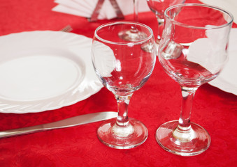 Two wine glass on a red tablecloth, decorated table,