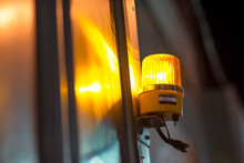 Close-up Detail Of A Yellow Revolving Warning Light Shining Onto A Metal Wall At A Construction Site. Industry And Construction Concept.