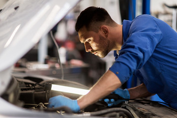 Wall Mural - mechanic man with lamp repairing car at workshop