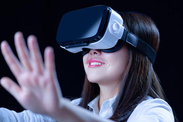 Asian Chinese young woman using vitual reality smart glasses in vitual space.low key photo