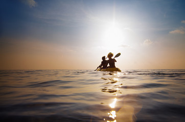 silhouette of people kayaking at sunset