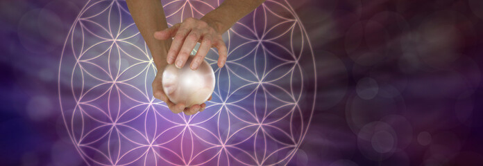 Wall Mural - Sacred Geometry and Crystal Ball Scrying - Female holding a large crystal ball above a Flower of Life Symbol on a wide purple bokeh background with copy space