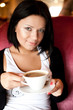 © Raisa Kanareva - young woman sitting in a cafe drinking coffee