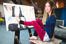 Disabled Beautiful Young Artist Painting Incredible Scenes In Attic By Holding Paintbrush In Her Toes.