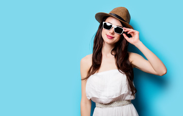 beautiful young woman in sunglasses standing in front of wonderful blue background