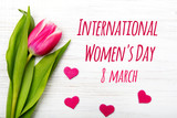 Fototapeta Tulipany - Women's day card. Tulip flower small hearts on white wooden background.