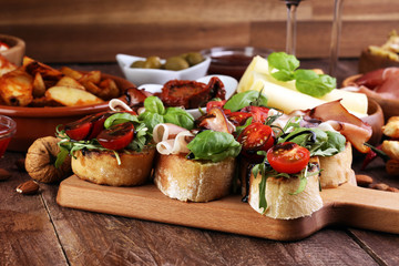 Italian antipasti wine snacks set. Cheese variety, Mediterranean olives, pickles, Prosciutto di Parma, tomatoes, artichokes and wine in glasses