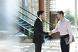 © PhotoAlto - Business people shaking hands while standing in the office lobby