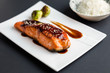 © lounom - Teriyaki salmon on black background. Japanese cuisine inspired dinner consisting of grilled salmon fillet glazed in delicious teriyaki sauce (soy sauce base). Brussel sprouts and white rice as sides.