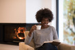 © .shock - black woman reading book  in front of fireplace