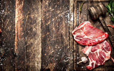 Raw meat background. Pieces of raw steak with spices and herbs. On wooden background.