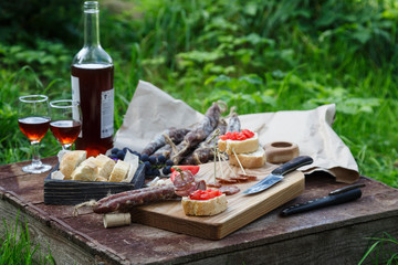 Sausage, tomato, bread and a glasses of red wine, contryside.